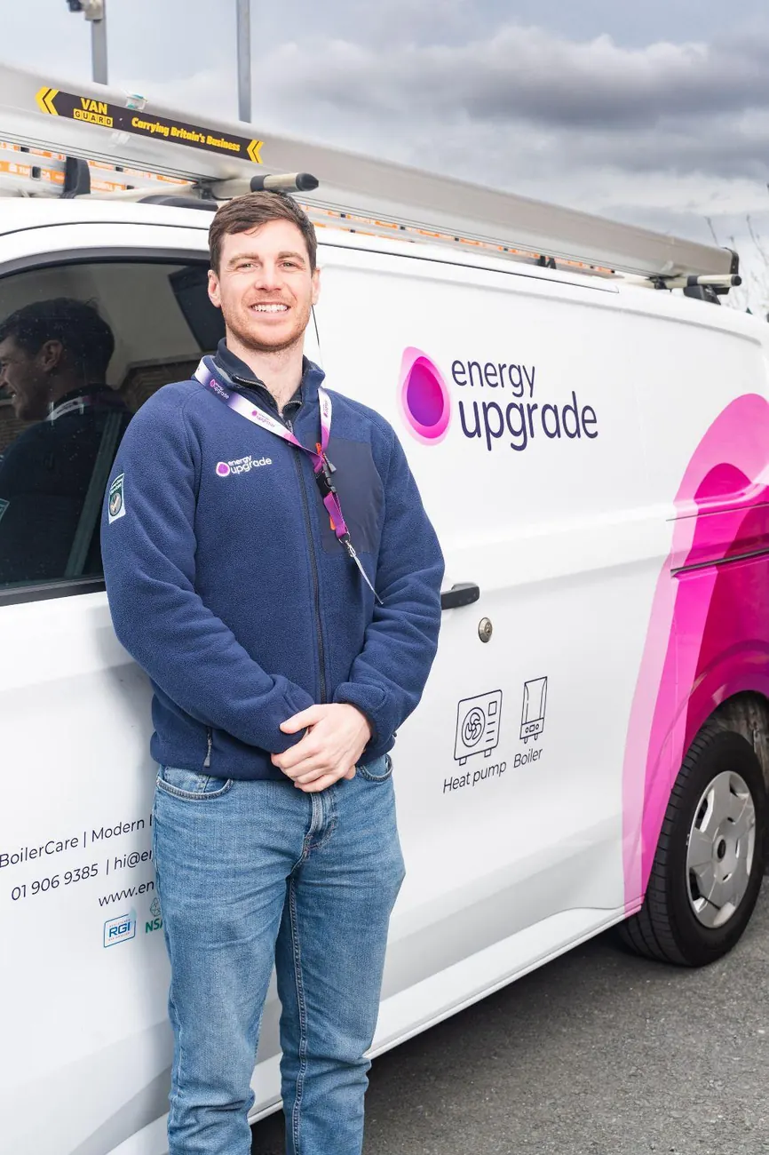 Energy Upgrade team member in the navy company fleece by a van