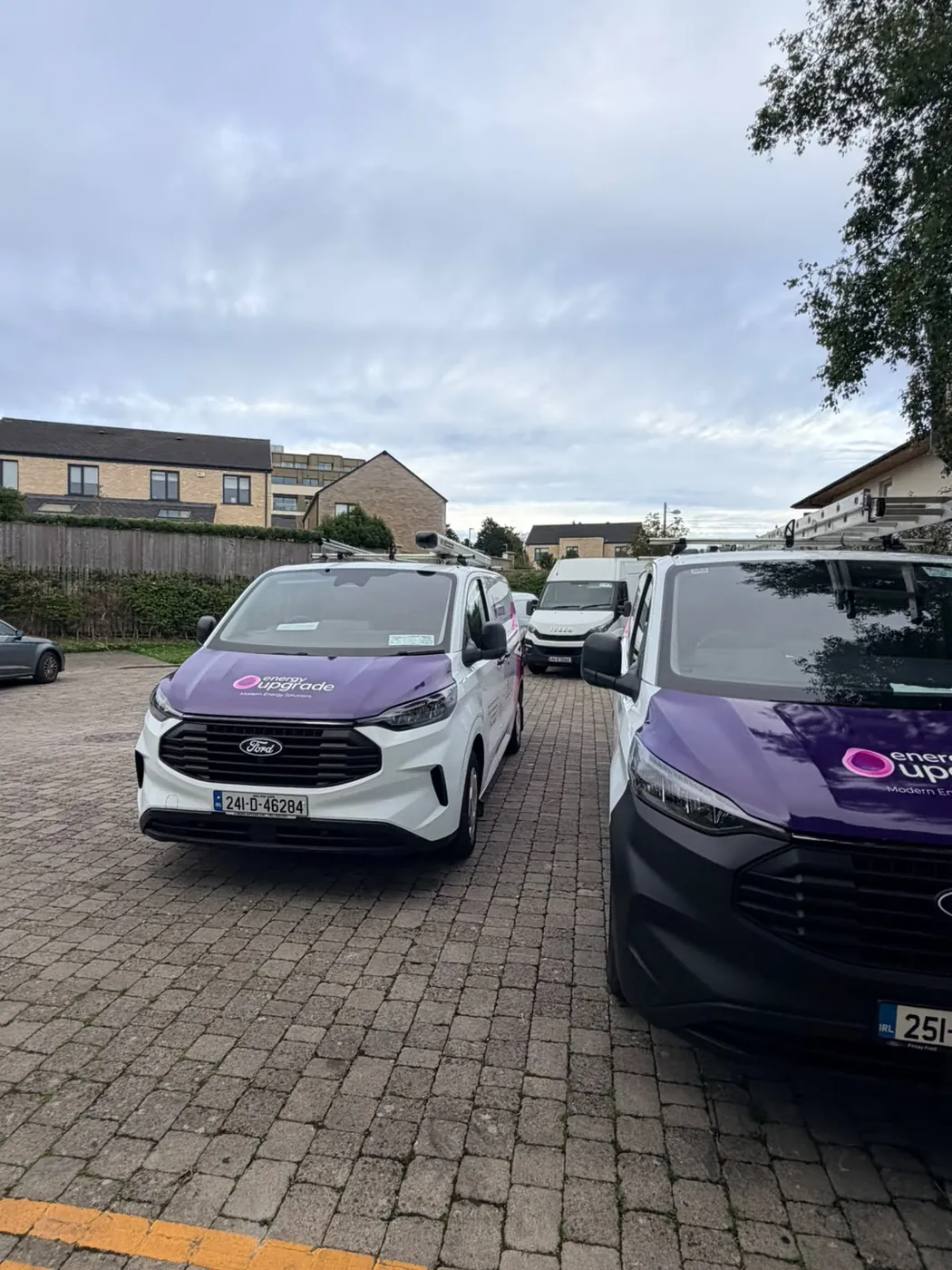 Energy Upgrade vans parked in a row on a residential street