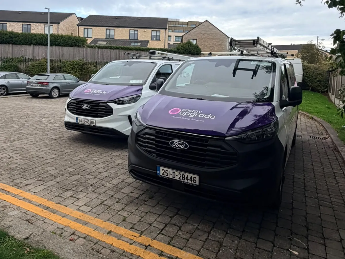 Two Energy Upgrade vans parked on a residential street